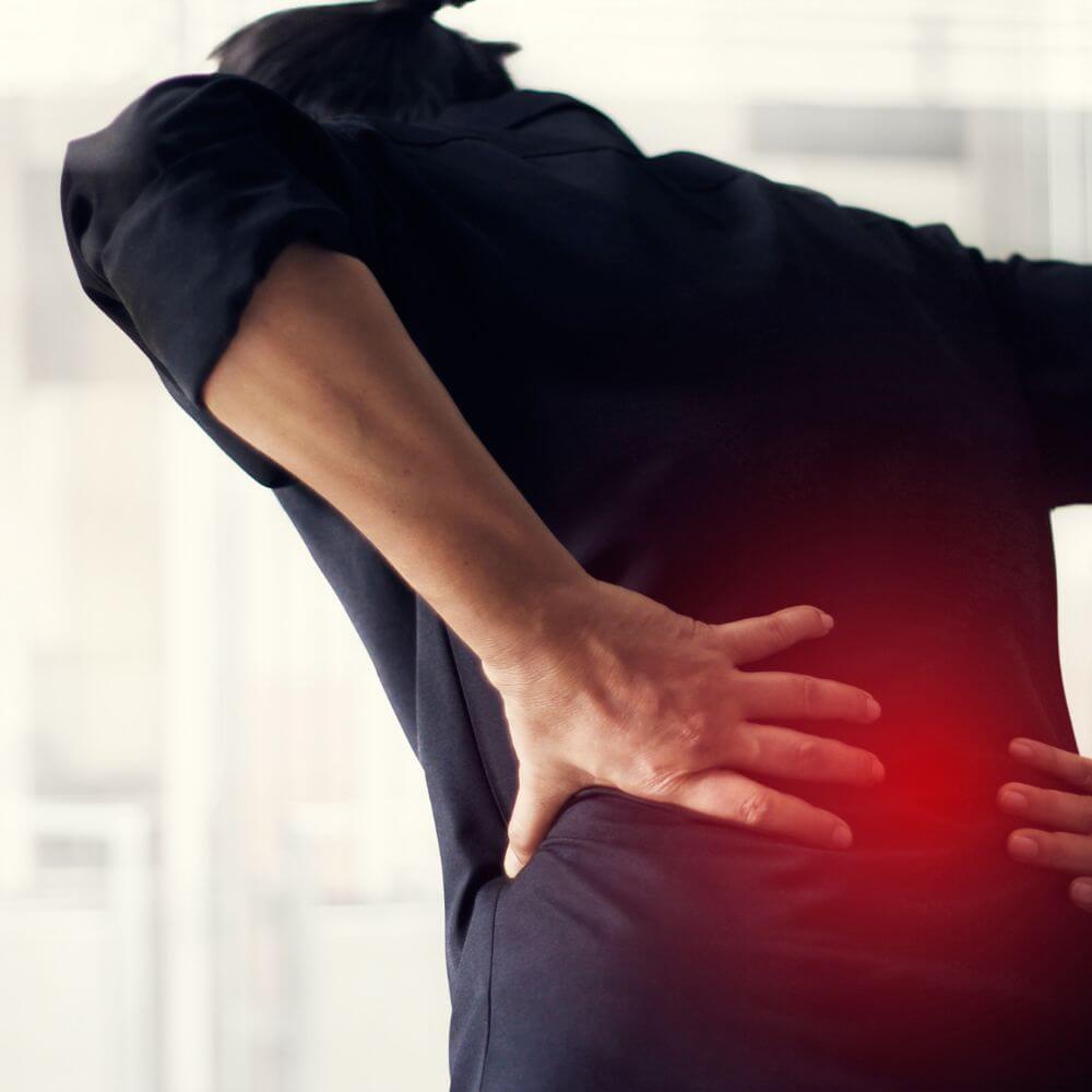 A person with their back turned is holding their lower back, indicating discomfort or pain.