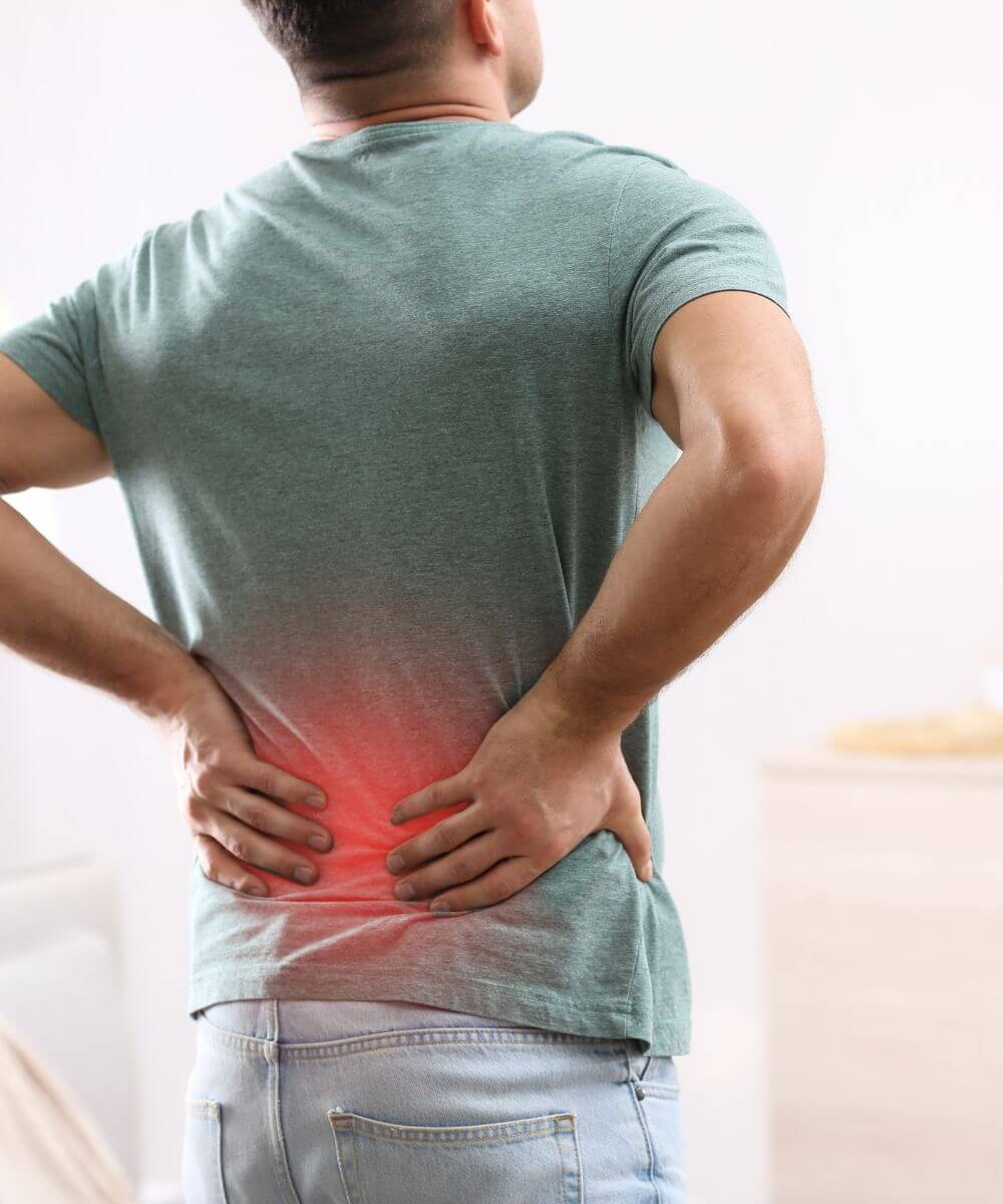 A person is holding their lower back, indicating discomfort or pain.