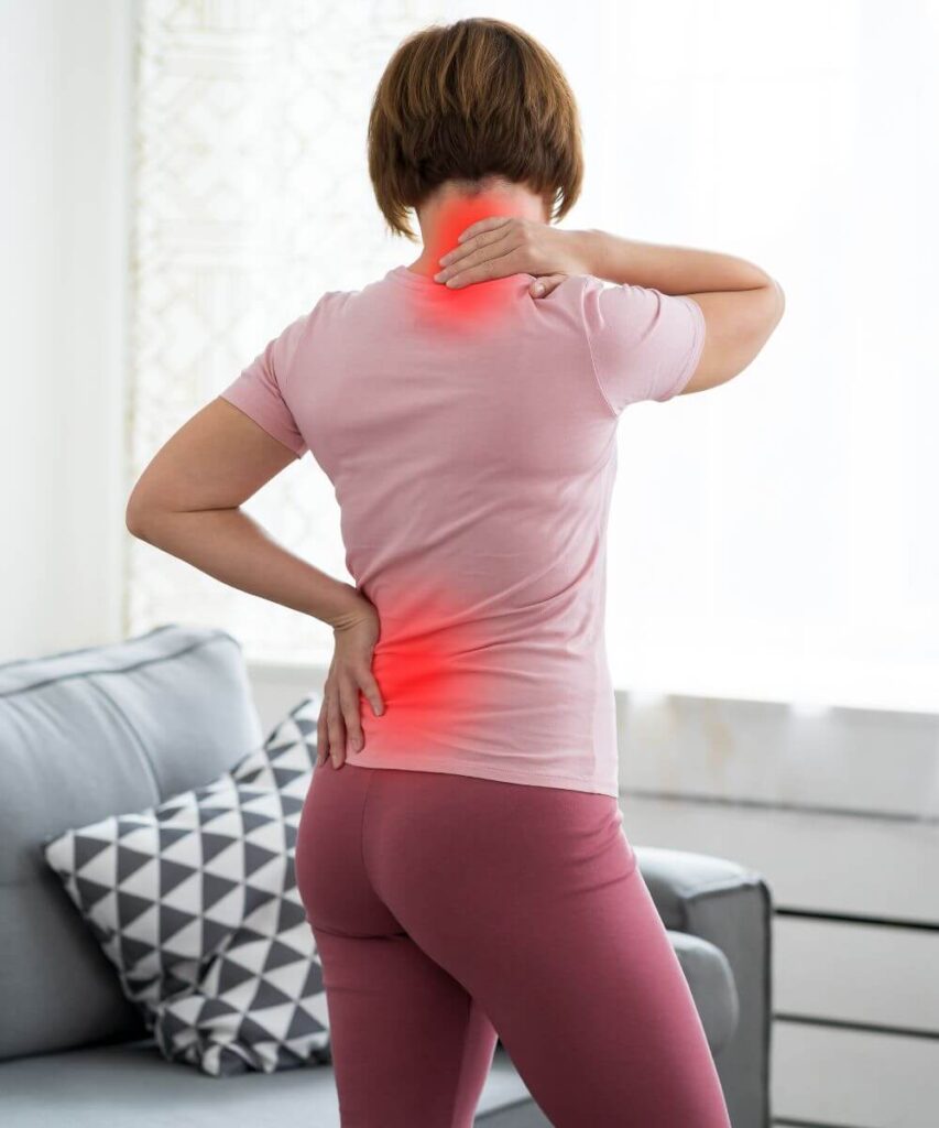 A woman is standing with her back turned, holding her neck and lower back, indicating discomfort or pain. The area in red highlights the locations of her pain.